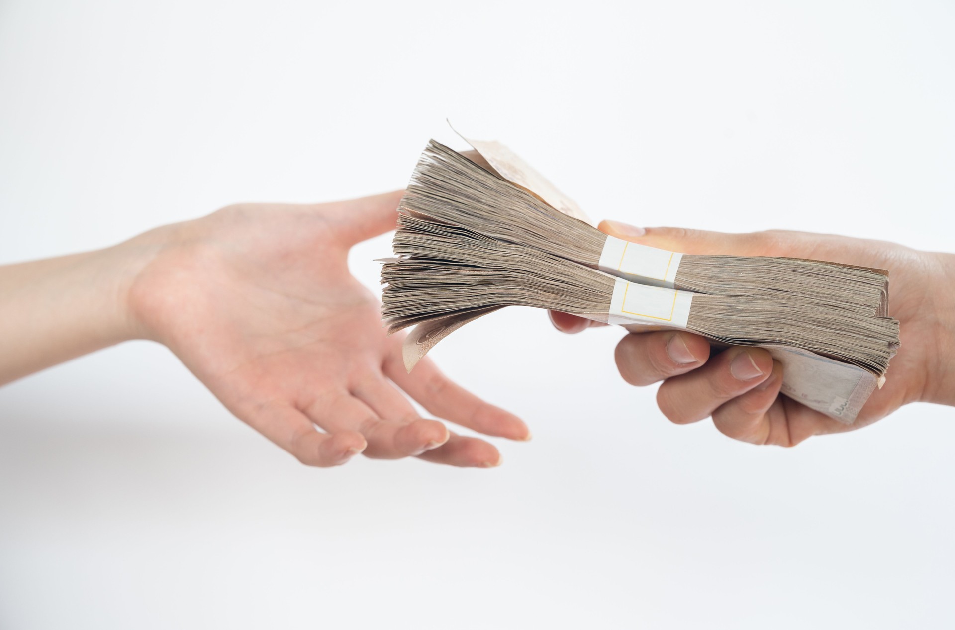 Close up of people giving packs of Thai baht money to other person isolated on white background.